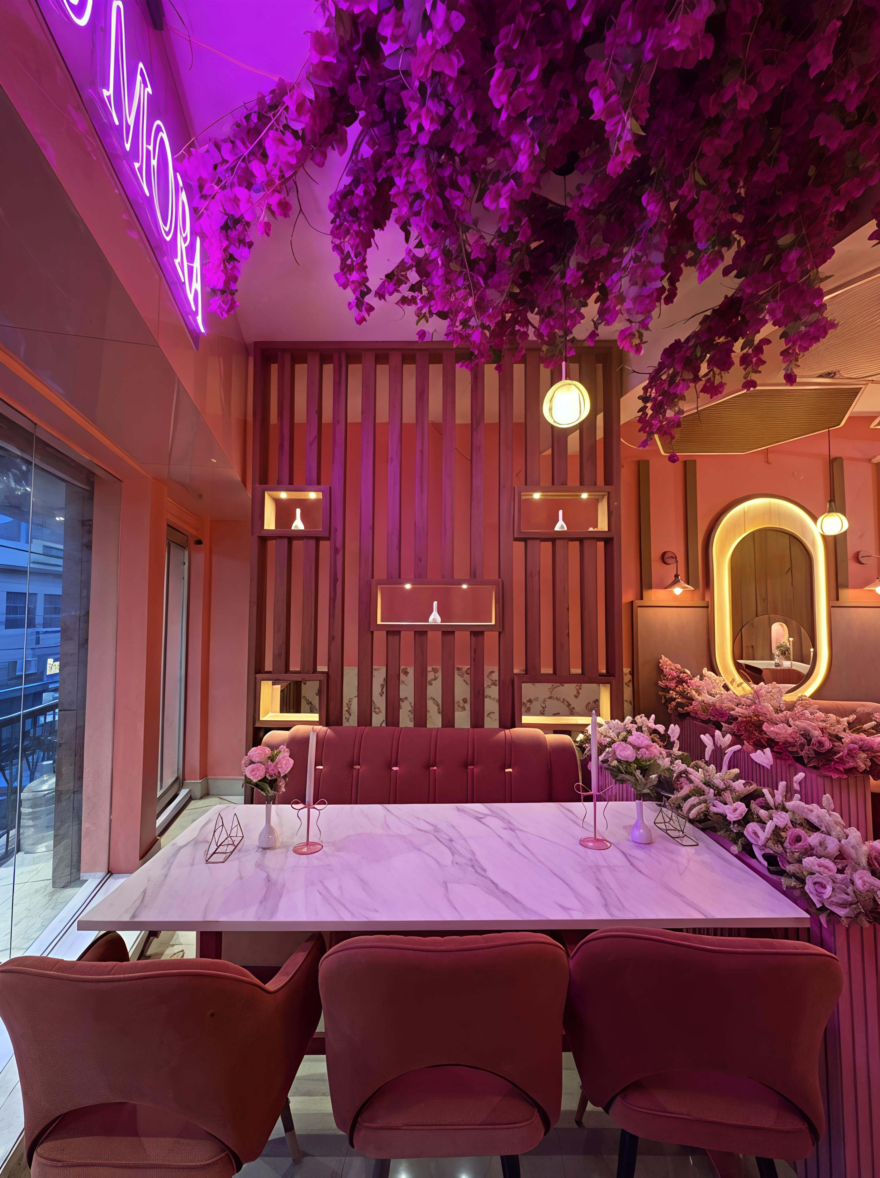 Bloomora dining floor — bougainvillea canopy, neon sign and marble family tables